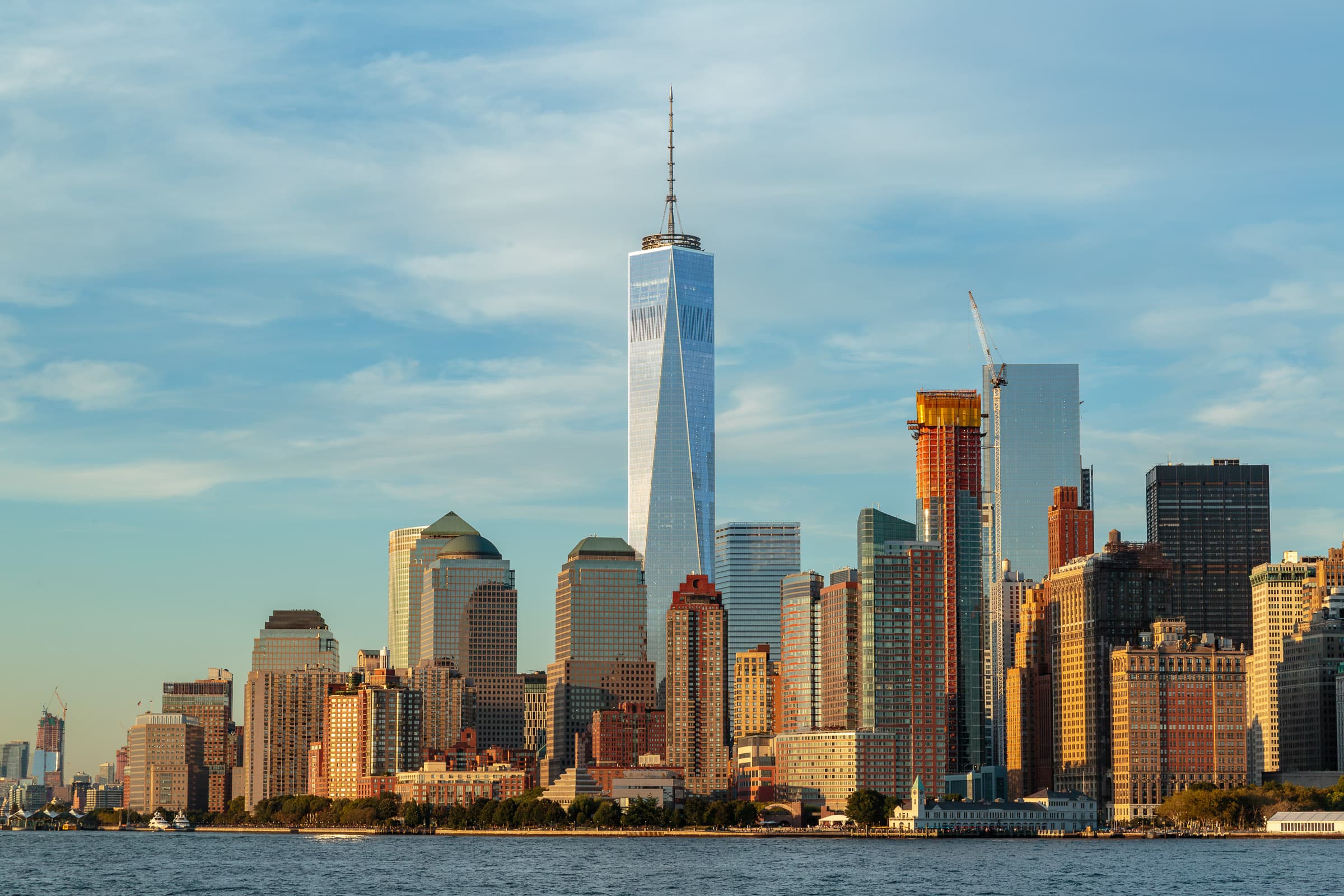 One World Trade Center rising above the Lower Manhattan skyline in warm September light, photographed from New York Harbor by Francisco Colón.