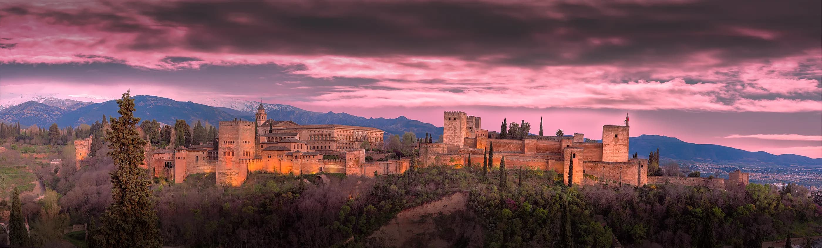Panoramic sunset view of the Alhambra and surrounding mountains from the Mirador de San Nicolás in Granada, titled Where My Journey Began — 1492 by Francisco Colón.