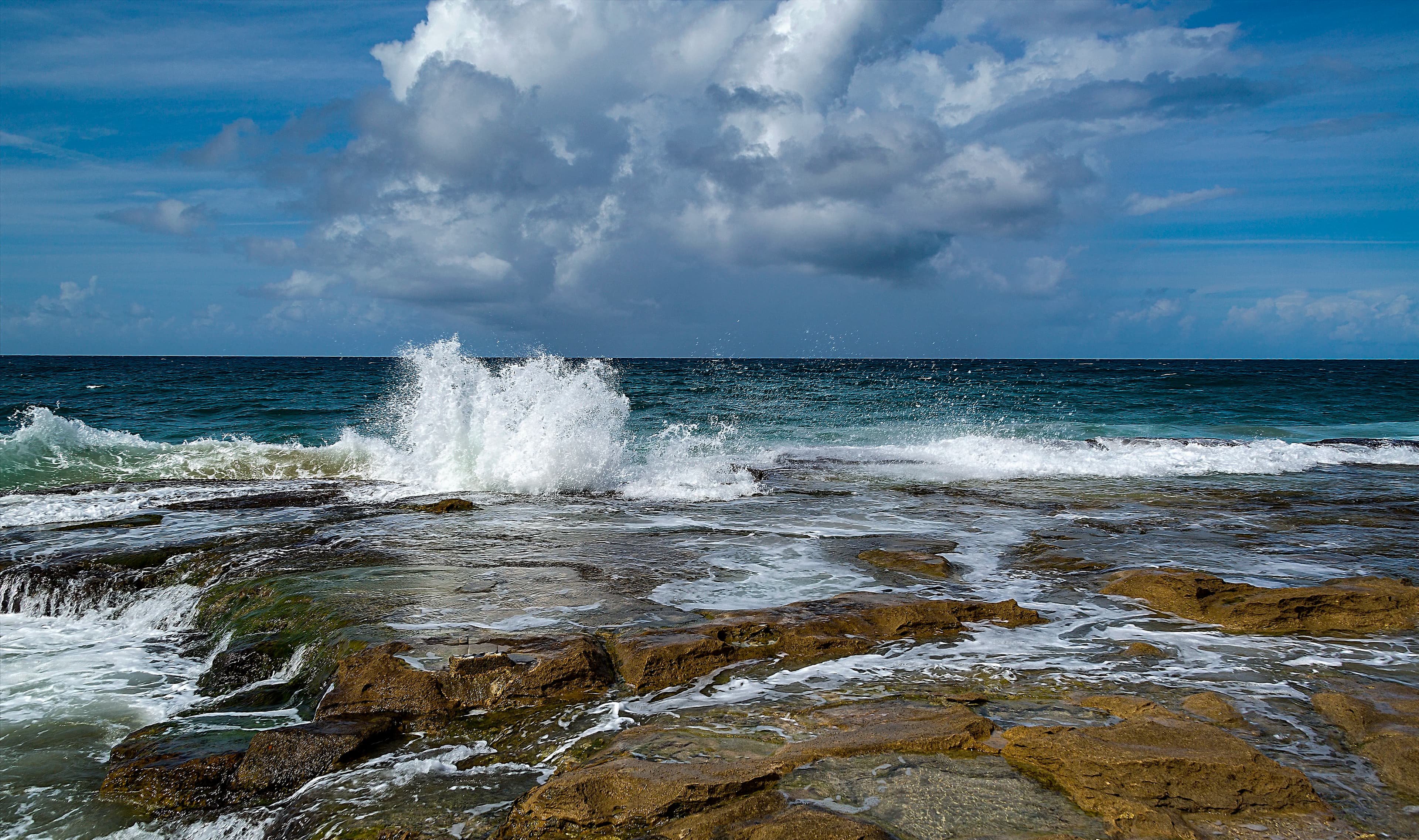 Atlantic wave exploding into suspended spray against the rocky coast of Quebradillas, Puerto Rico, titled Where the Ocean Speaks by Francisco Colón.