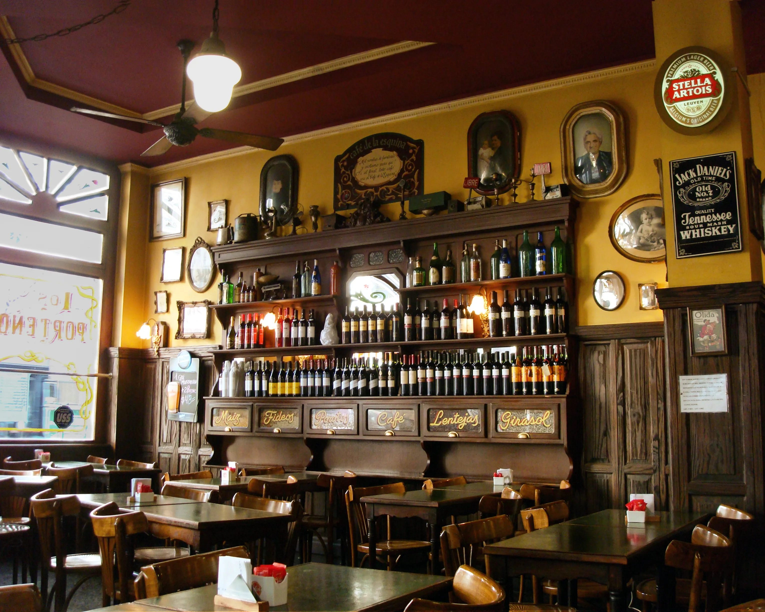 Empty vintage-style neighborhood café interior in Palermo, Buenos Aires, with tables, bar, bottles, and mirrors, titled Echoes of the Corner Café by Francisco Colón.