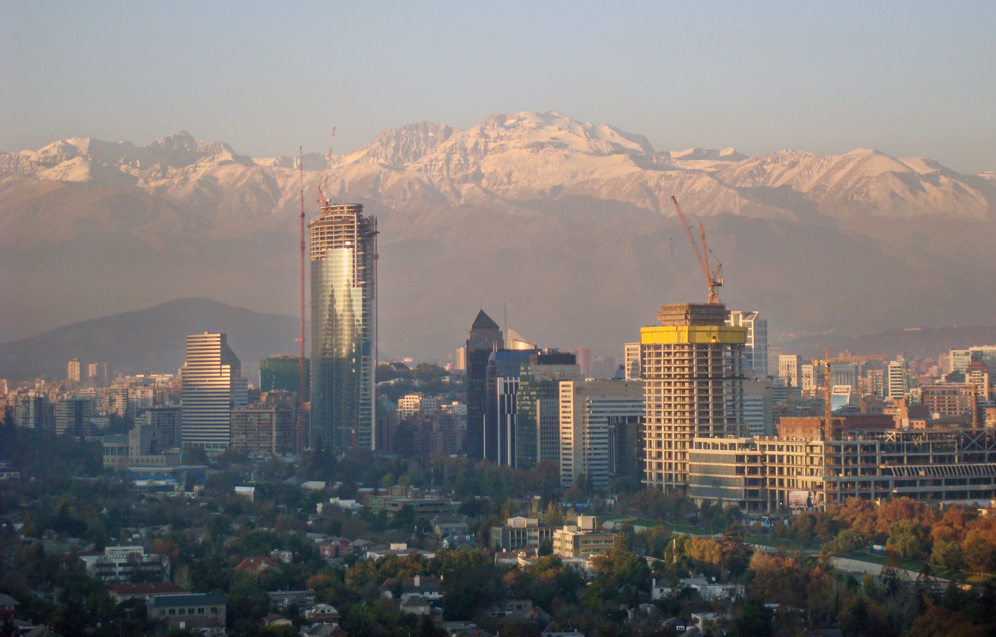 Santiago, Chile beneath the snow-covered Andes Mountains, with construction cranes and buildings rising across the city in May 2009.