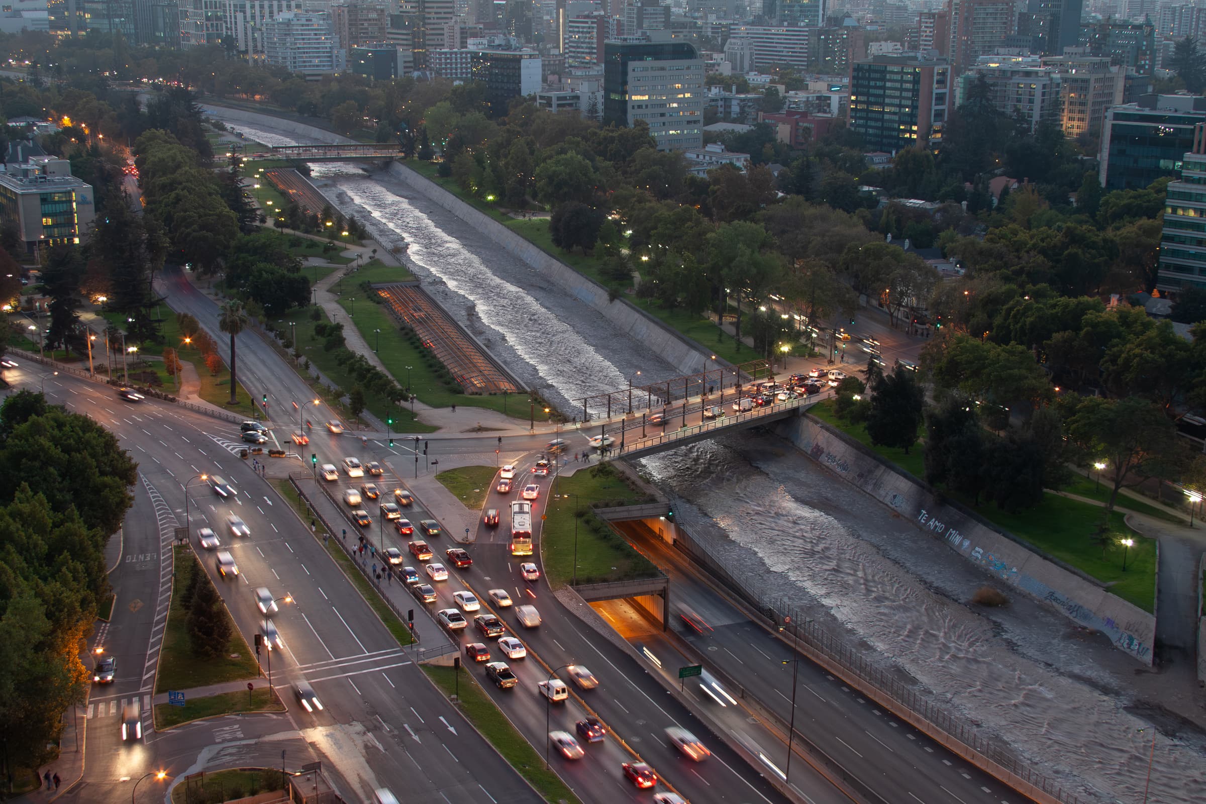 Daybreak view over Santiago, Chile, with traffic converging at a bridge and water flowing through a channel toward distant buildings.