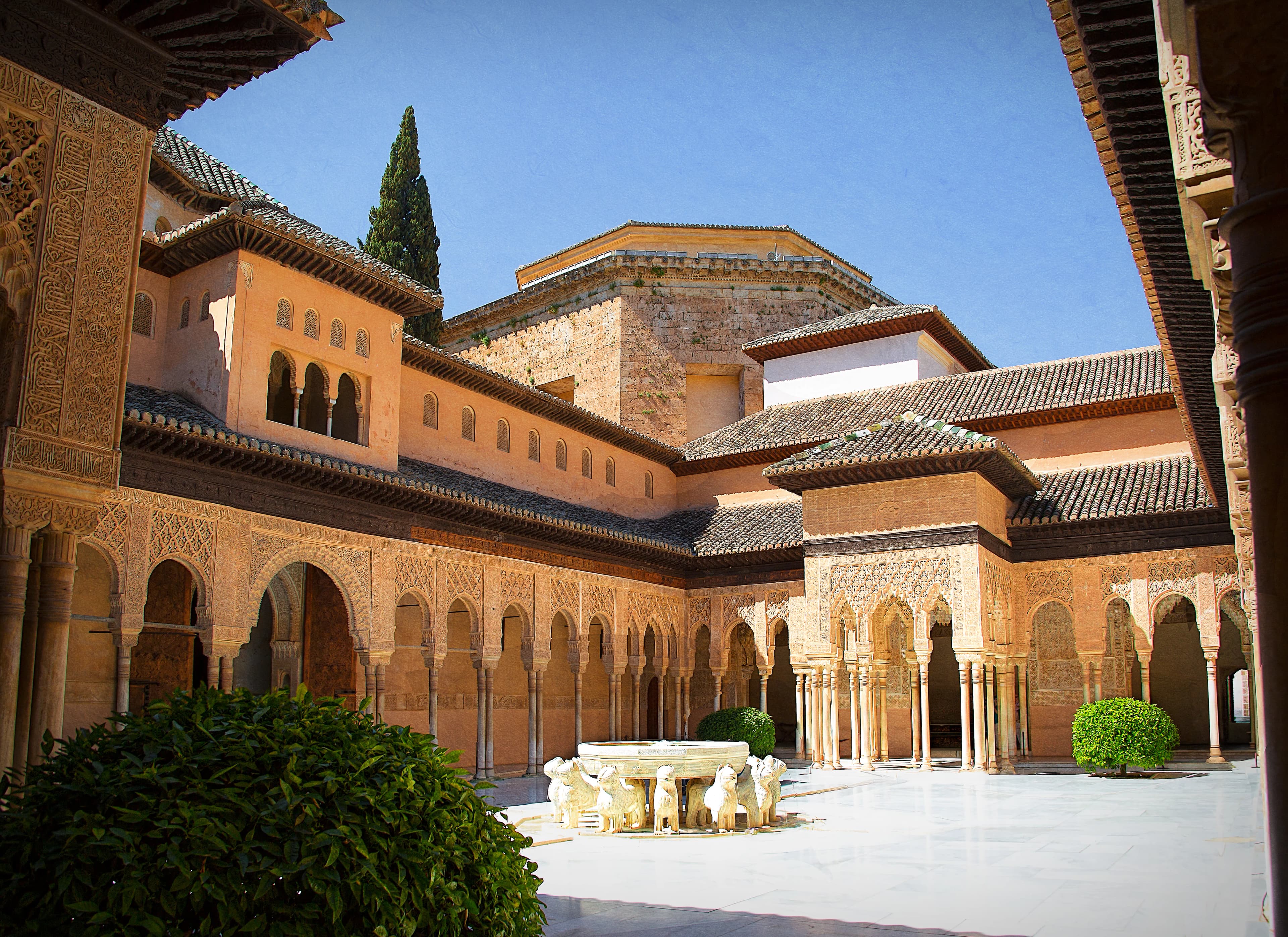 Panoramic interior of the Court of the Lions at the Alhambra in Granada, showing ornate arches, corridors, waterways, and the central fountain, titled Within the Heart of the Alhambra by Francisco Colón.