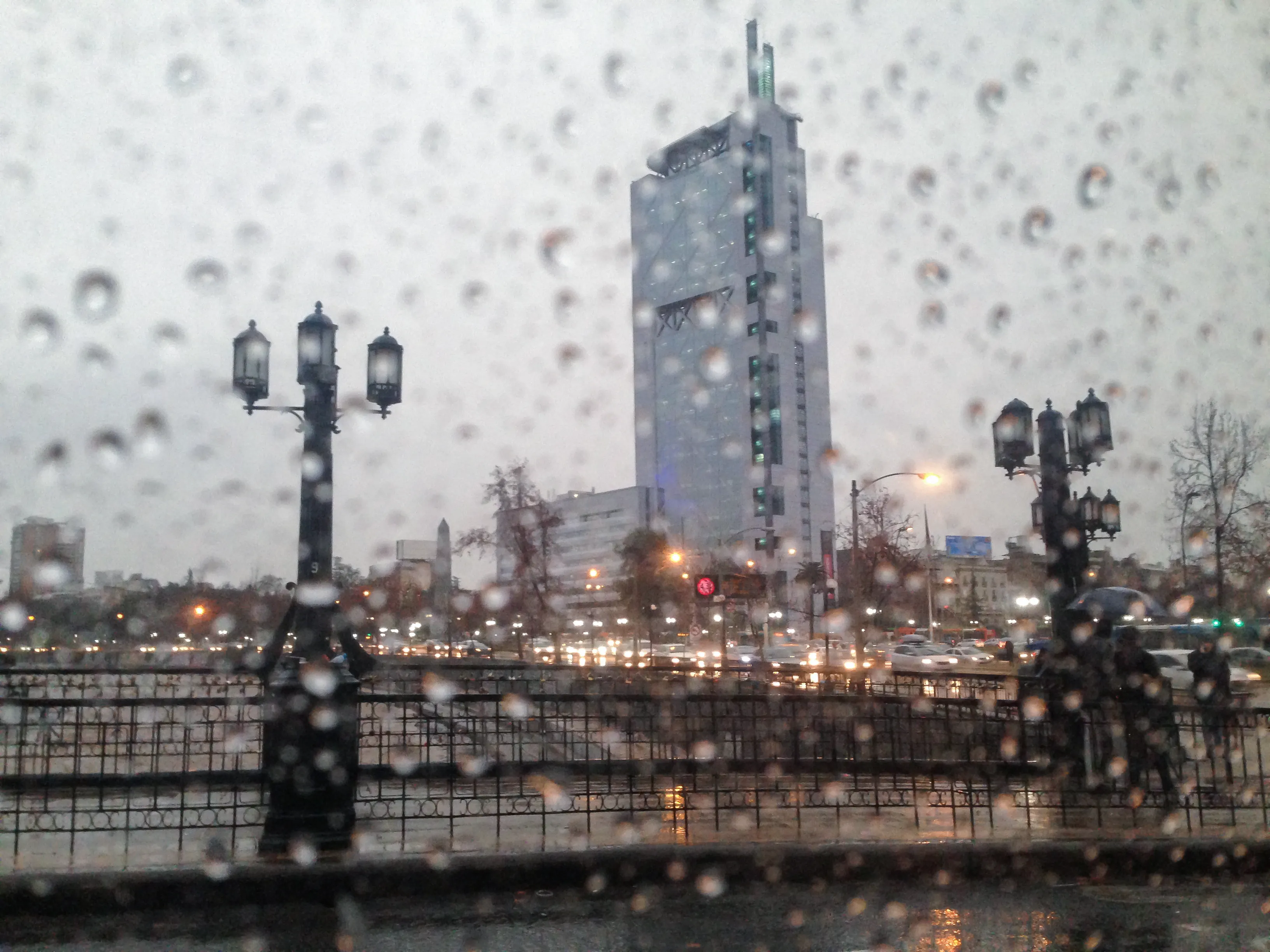 Raindrops covering a taxi window with Santiago, Chile visible through the rainy glass during a morning arrival in August 2015.