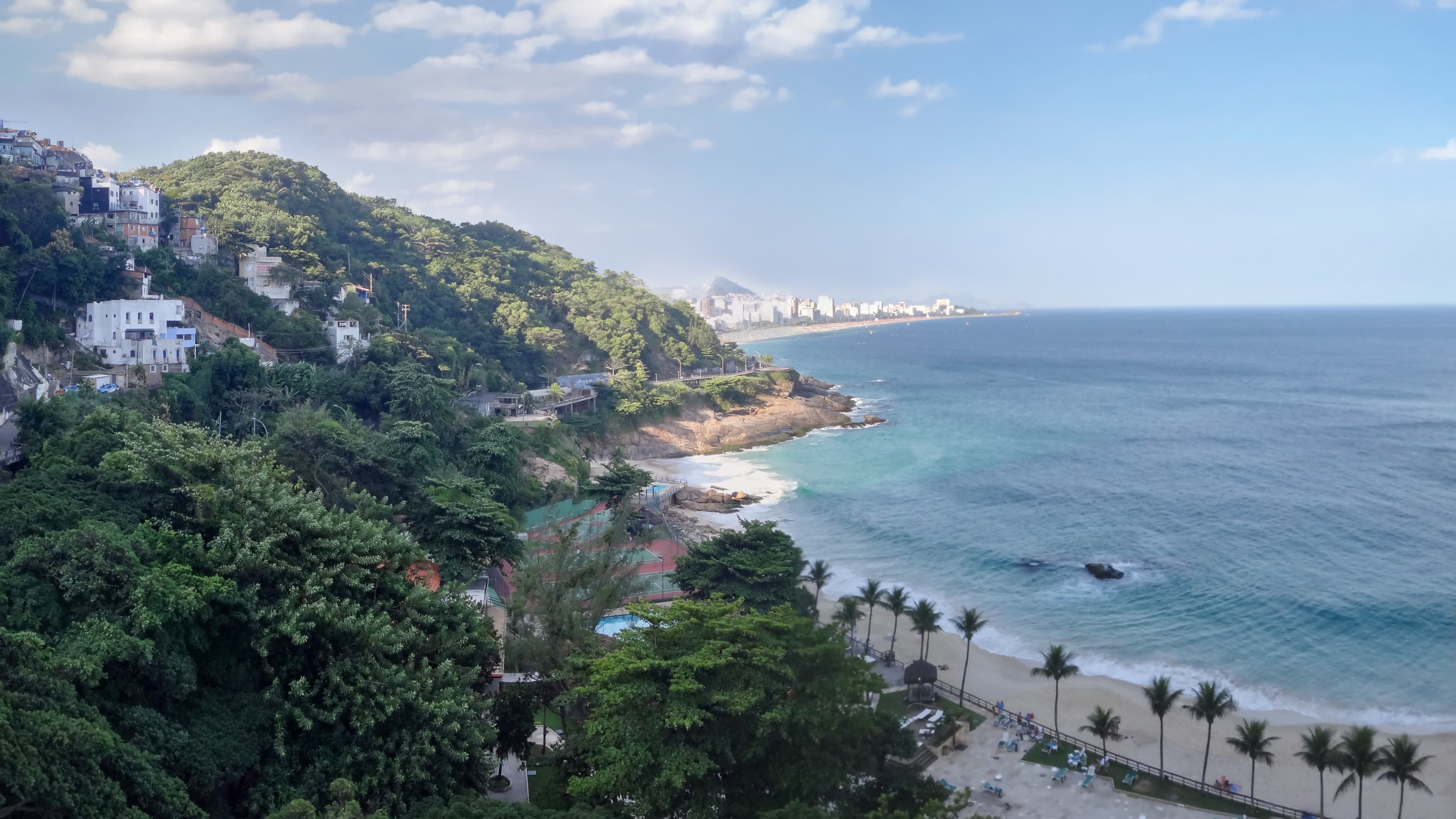 Elevated view from the Sheraton Hotel across a forested hillside, Atlantic coastline, and distant neighborhoods of Rio de Janeiro, titled The View I Asked For by Francisco Colón.