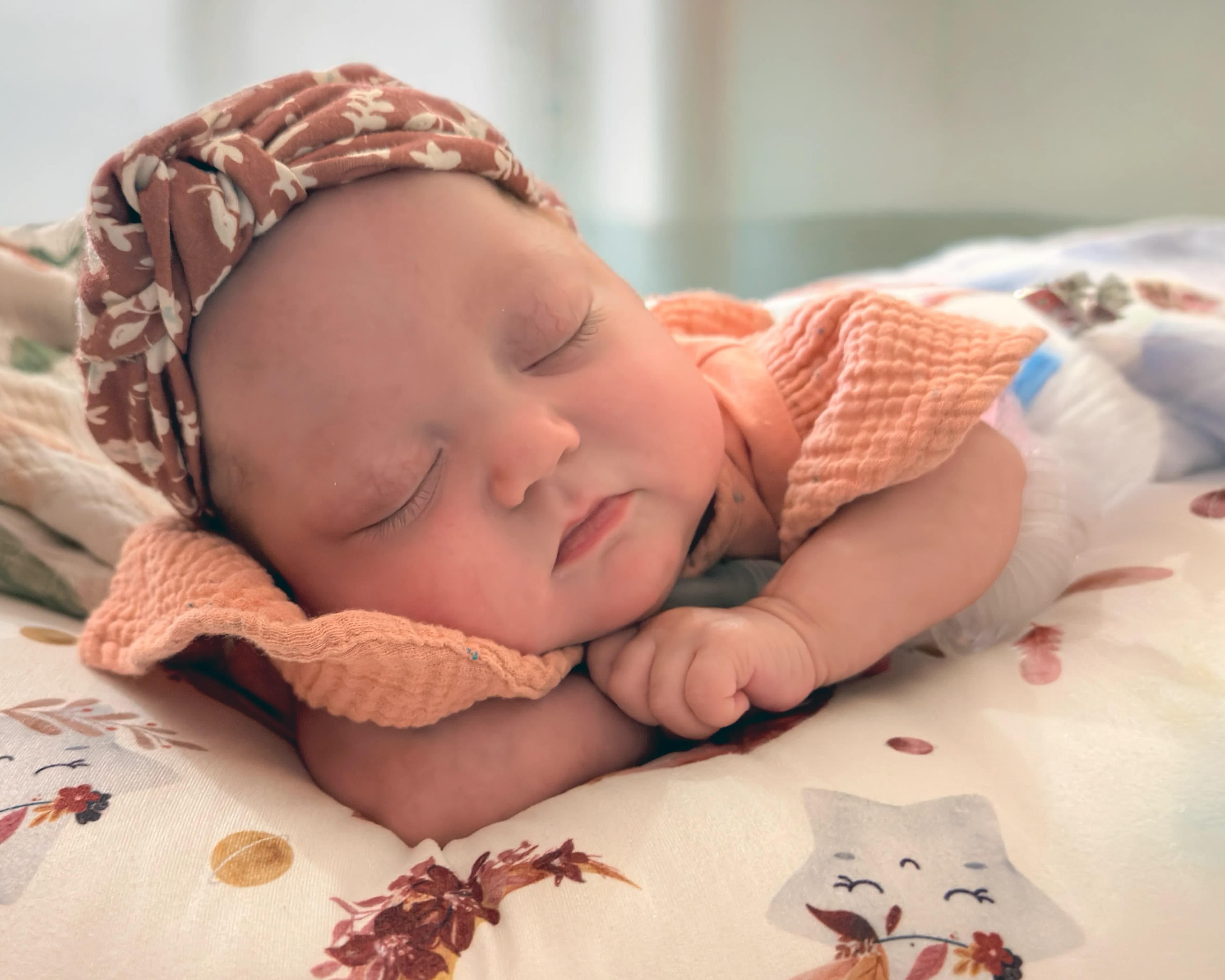 Newborn Sofia Luz sleeping peacefully on a soft white blanket and wearing a headband, titled Sofia Sleeping on the Moon by Francisco Colón.